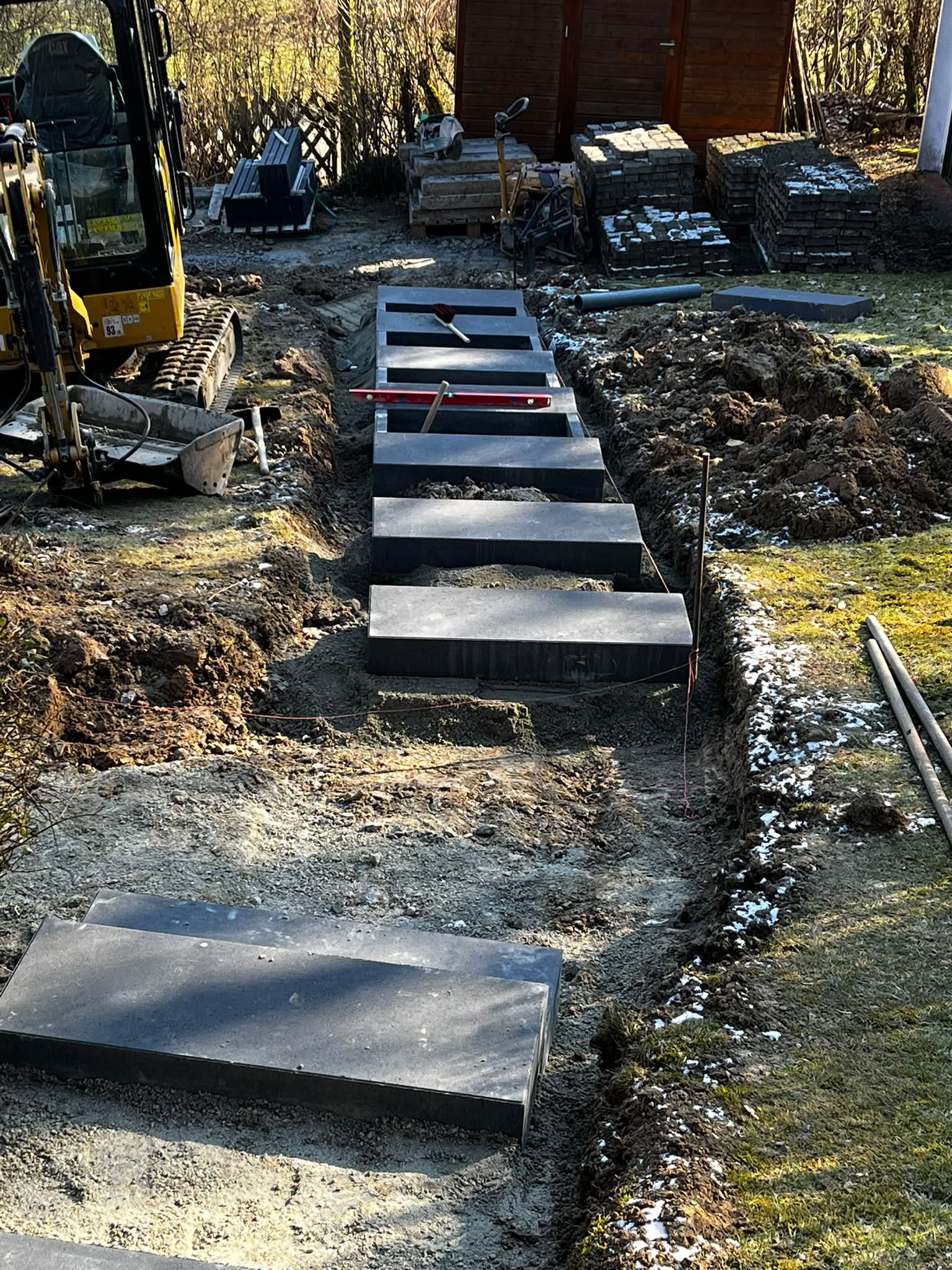 Pflasterdonner-Team beim Setzen von Blockstufen mit dem Minibagger